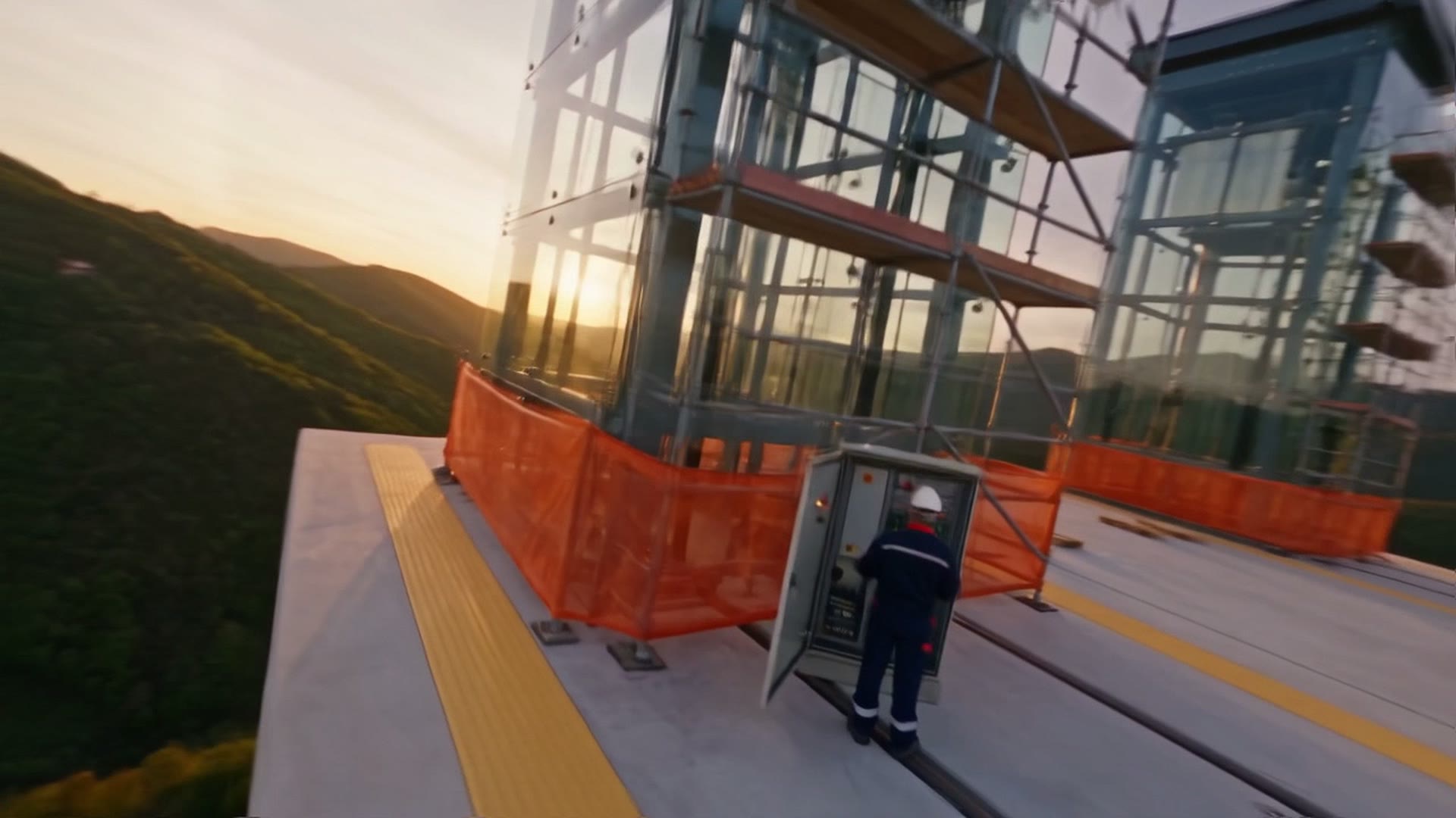 Il tecnico con il casco davanti al quadro di manovra aperto, al tramonto