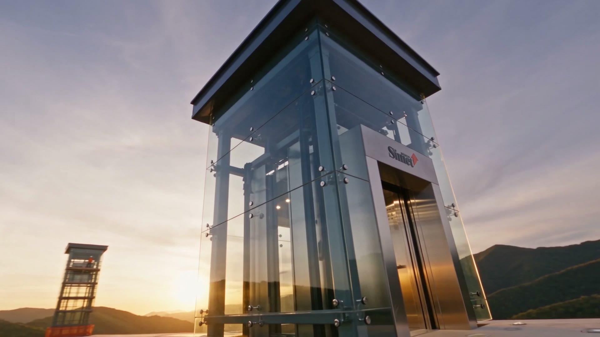 Una torre in vetro e acciaio con un ascensore panoramico, su un terrazzo al tramonto
