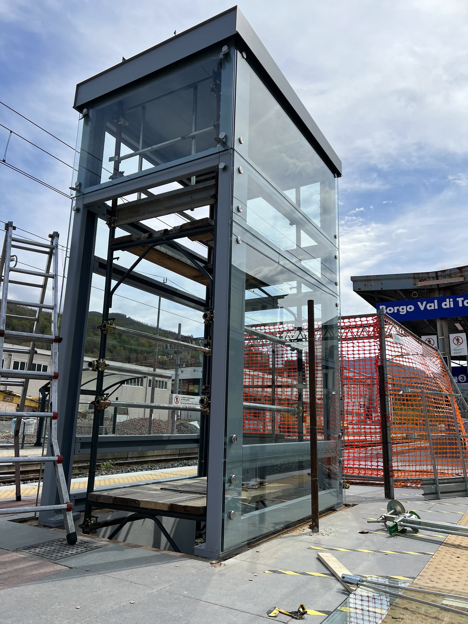 Il vano in vetro e acciaio di un ascensore sul marciapiede di una stazione ferroviaria