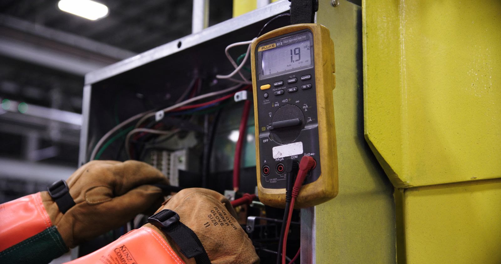 Un elettricista ripara il cablaggio di un quadro con il multimetro