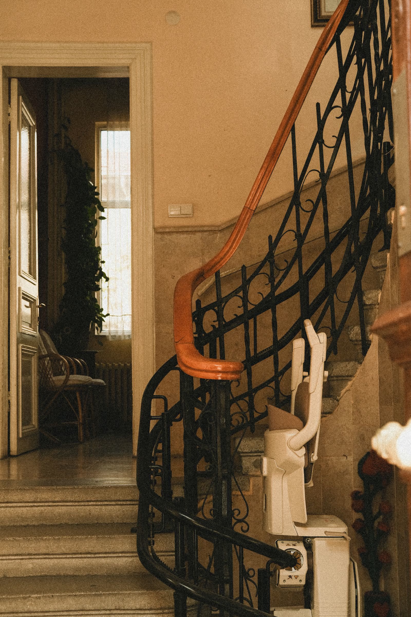 Una scala interna con ringhiera in ferro battuto e la guida di un montascale